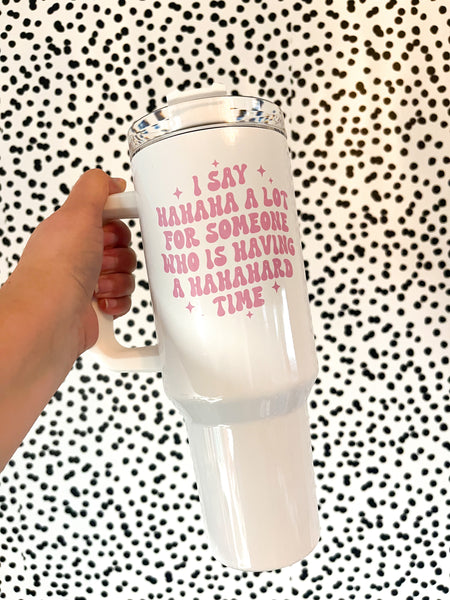 Pink font that says I say hahaha a lot for someone that is having a hahahard time on a 40oz white tumbler with a handle.