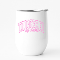 Pink font that says triggered by idiots on a a white wine tumbler